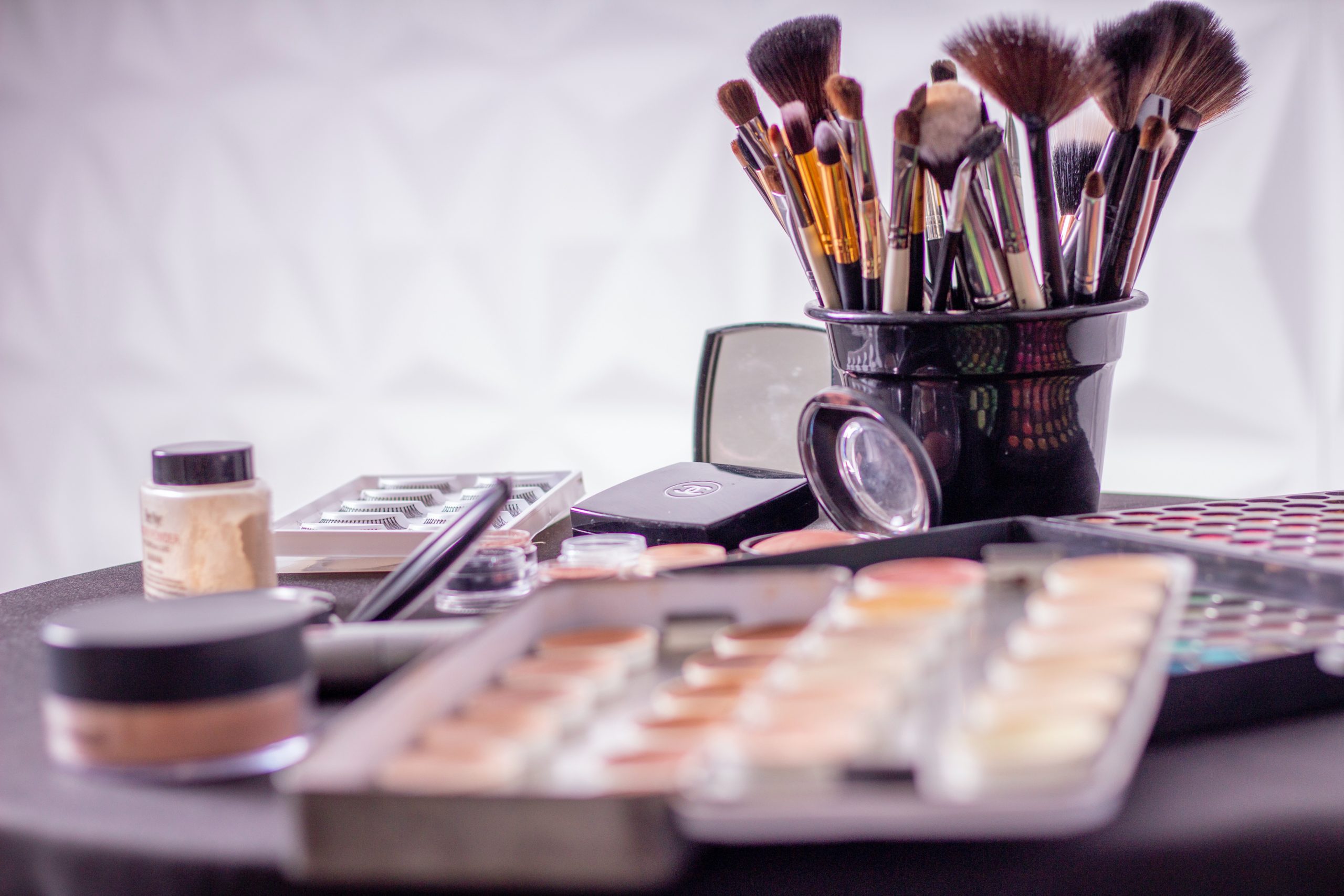 Cosmetics on a table, including eyeshadow palettes and brushes.
